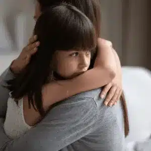 A worried child hugs mother during legal talks on how do I file for custody of my child