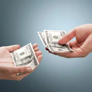 Hand giving money illustrates the legal responsibility of child support payment in Montana