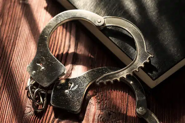 Close-up of handcuffs resting on wooden table with book, symbolizing expungement Montana legal process